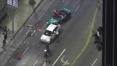Protesters chase a vehicle down, smash the windows with a skateboard while attempting to pull the driver out of the car. After speeding away the driver is being handcuffed by LAPD