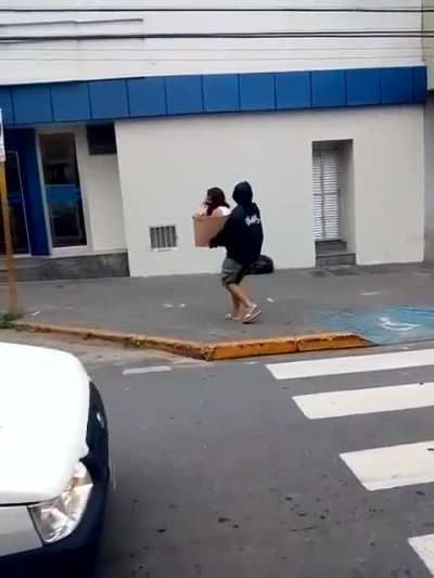 Man carrying another man in cardboard box