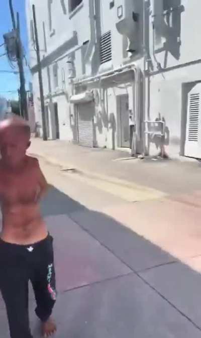T-Rex looking dude armed with scissors on his foot chases a guy down the street.