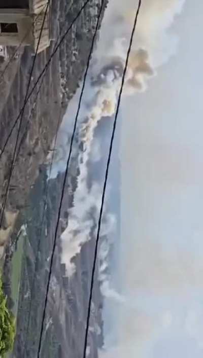 Hezbollah munition cache hit by an Israeli airstrike cooks rockets off, sending a rocket to a nearby building 