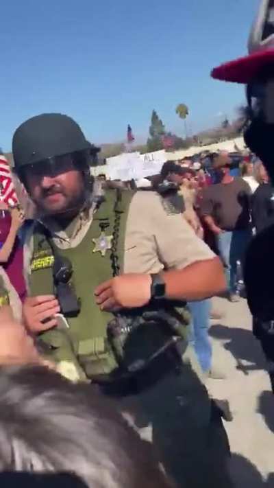 Sheriff's deputies ignore a neo-Nazi attacking a female peaceful protester