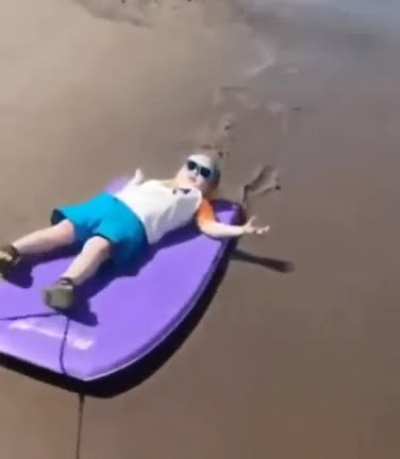 Cool baby being pulled on a bodyboard
