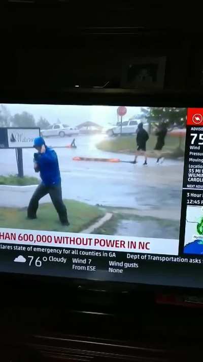 Reporter braces against the wind during a live shot