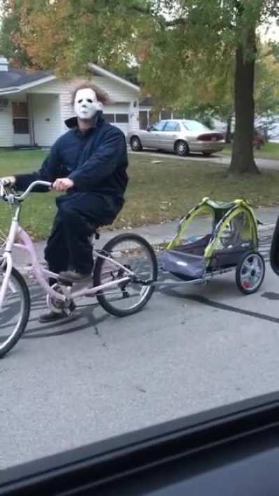 Father stays in character, riding a pink bike as Michael Myers.
