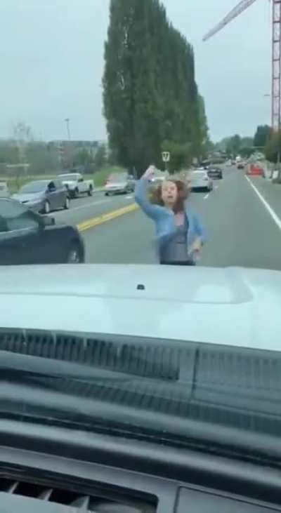 Girl stands in the road jumping up and down while yelling 