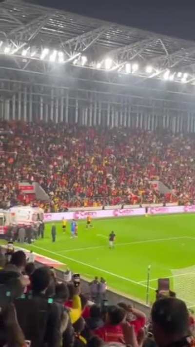 Supporter breaks corner post on goalkeeper's back.