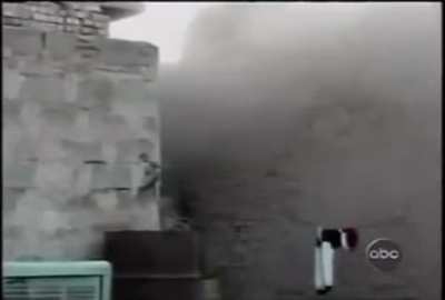 A marine throws a grenade at an Iraqi insurgent who fell down between two buildings, and then finishes him with his rifle.