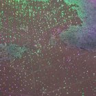 Lights at a botanical garden reflecting onto a puddle while raindrops fall onto it, look like mini fireworks