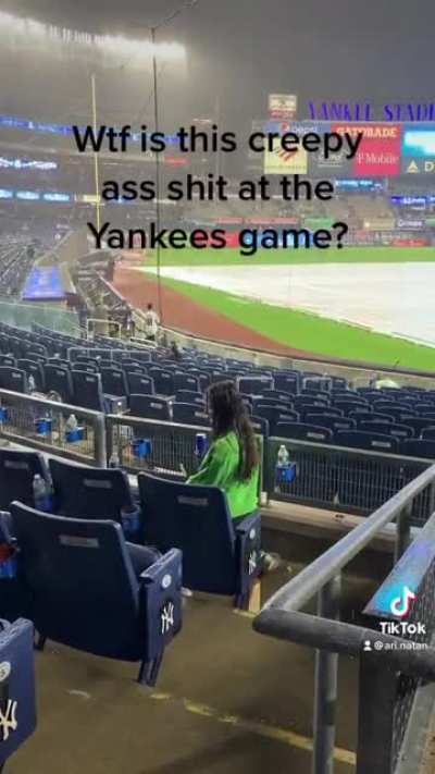 This girl sitting in the rain at the rain delayed Yankees game.
