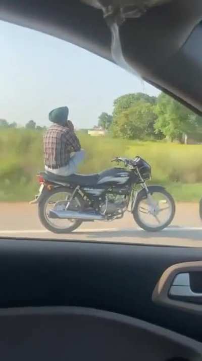 Telephonic dude on a motorcycle unconcerned with steering