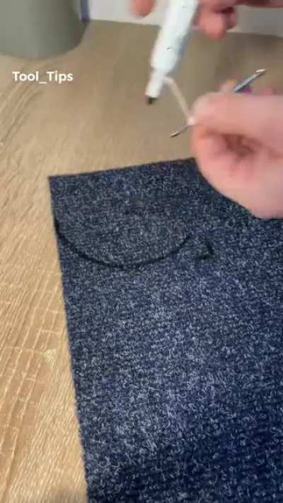 Cutting carpet to fit around a pipe.