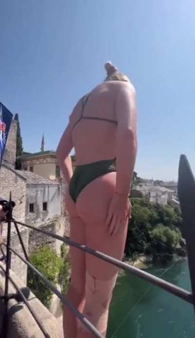 Woman performs a very high dive off a bridge