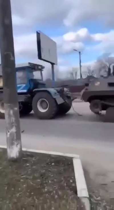 Soldier hauling russian tank away with tractor, filmer throws stones