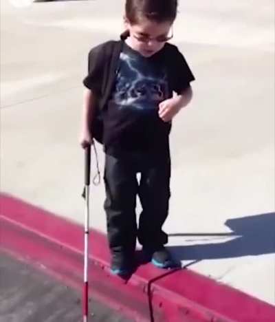 Blind kid experience his first curb by himself while his parents encouraged him.
