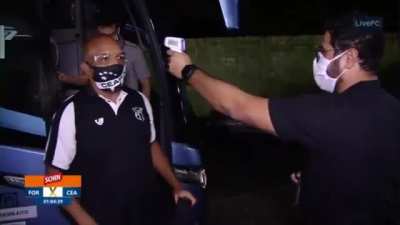 Organizers taking the temperatures of the people getting off the bus at a Brazilian football clubs meeting.