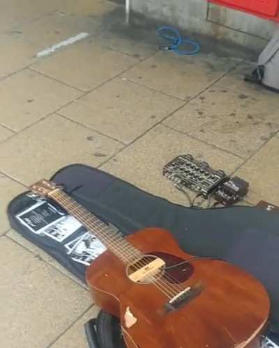 Woman destroys a buskers guitar because she didn't like his music.
