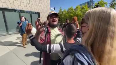 Man attends an anti-Dave Chappelle Netflix protest with a sign that says, 