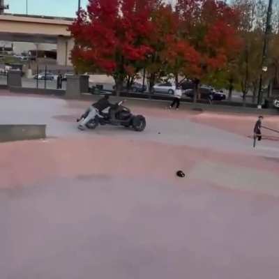 Trike with a dude hanging for dear life on a skatepark