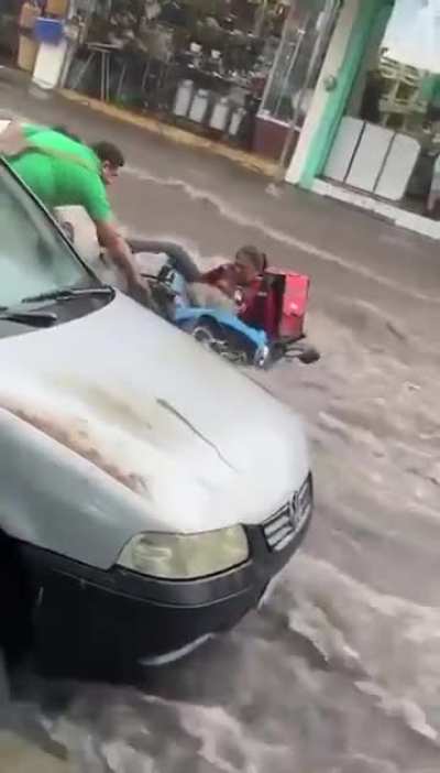Una joven repartidora de comida estaba siendo arrastrada por la corriente en una calle de Colima. Tuvo que ser ayudada por varias personas.