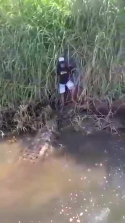 Caiman has a kid cornered and at its complete mercy. Extremely lucky the boat turned up. I would have shat my entire intestinal system out!