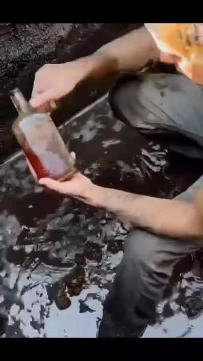 This guy finds a 100-year-old bottle digging in the mud