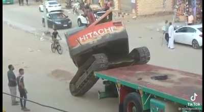 Egyptian driver loading off an excavator from a trailer truck