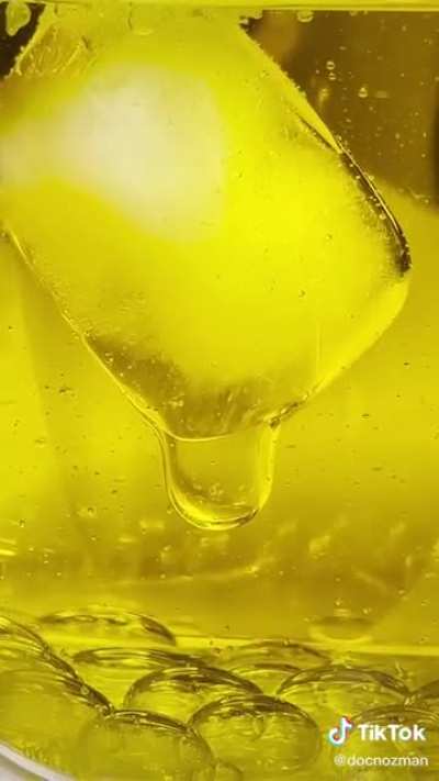 A cube of ice melting inside oil