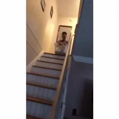 Trying to slide down the stairs in a laundry basket