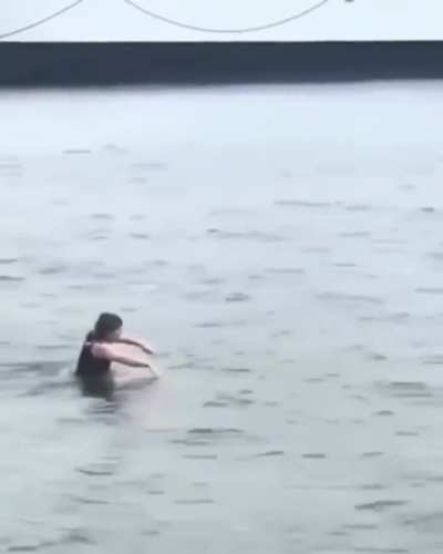 Cruel young woman abandons helpless cat in harbor basin.