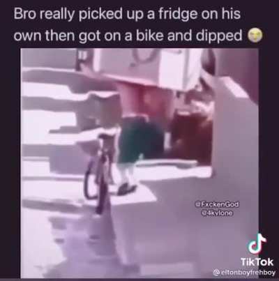 homeless guy bikes with a fridge on his back