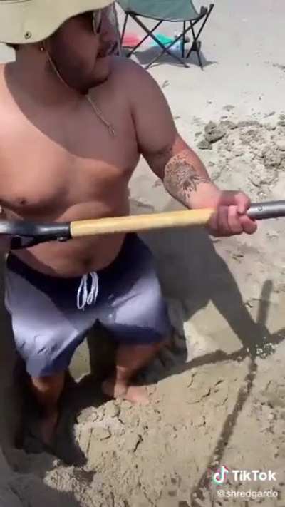 2 guys digging a hole at the beach