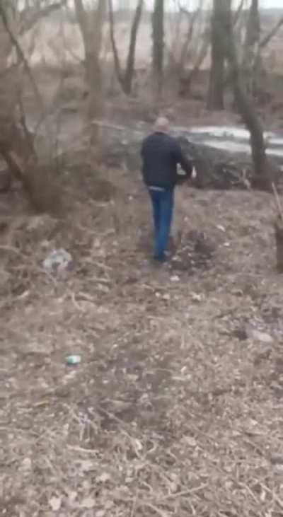 Ukraine, Berdyansk. This man found a mine near the bridge and houses. With his bare hands and a cigarette in his mouth, he carried it into a forest.