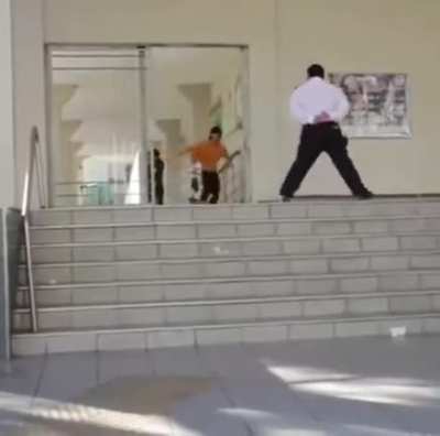 Skateboarding off some stairs whilst security guard watches intently