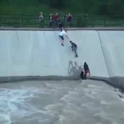 Drowning dog is saved by a group of madlads forming a human chain.