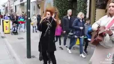 Woman with wild hair disrupts an acoustic street performance