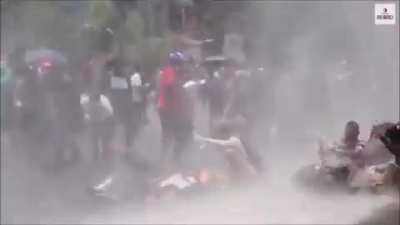 Protestor shielding water cannon with umbrella