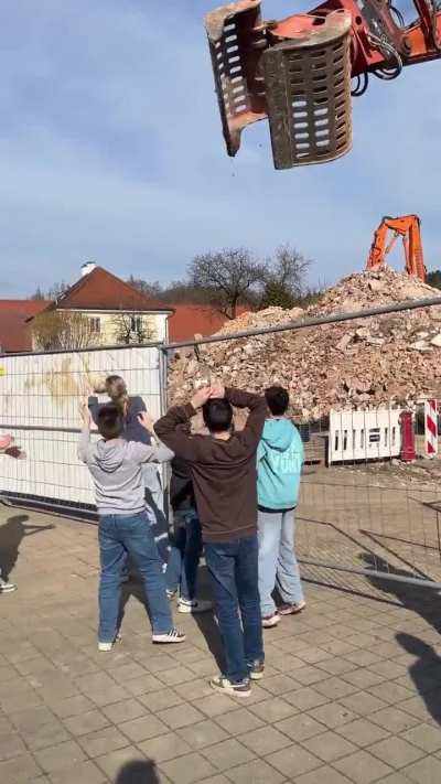 The construction worker skillfully operated the machine and returned the ball to these teens.