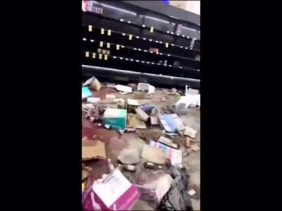 Woman breaks down as she walks through a store which was ransacked by looters