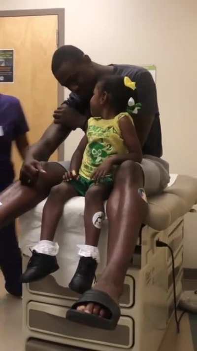 Father pretends to get vaccinated first so daughter is less scared by the needles.