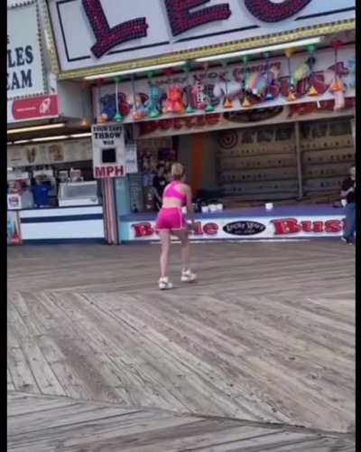 A crowd gathers to cheer on a woman taking her carnival games seriously