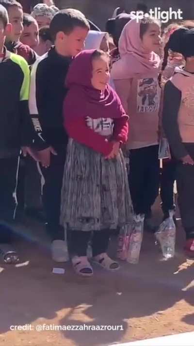A shy little Syrian girl can't hold back her excitement at this humble children's event.