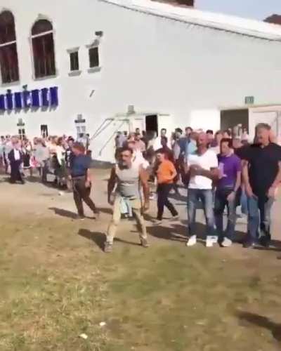 This dude is hammered-drunk and trying to to put his shoe back on. A crowd gathers to cheer for him.