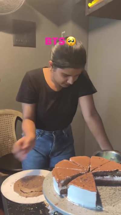 Woman decorating a cake spins the stand and watches slices fall off