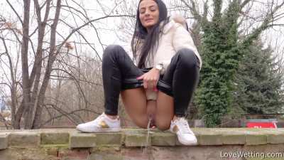Silvia Black pees off the wall by the road as vehicles drive by