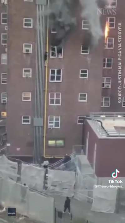 A pair of teenagers climb out the window of a burning apartment