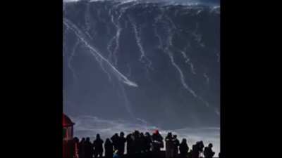 A human surfing an incredibly large wave